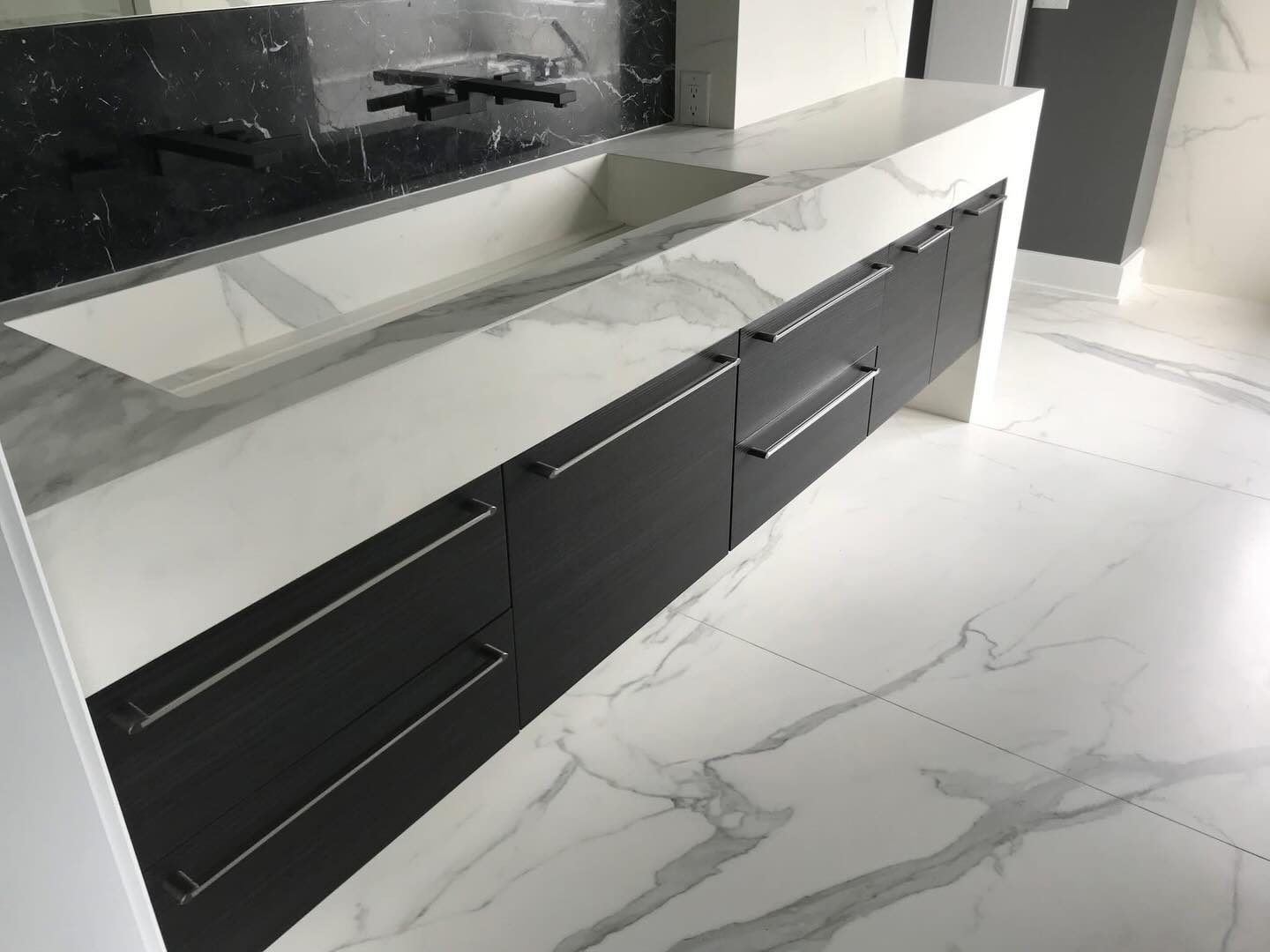 Black flat-panel cabinets under a marble top by Shoreline Cabinet Company, Wilmington NC