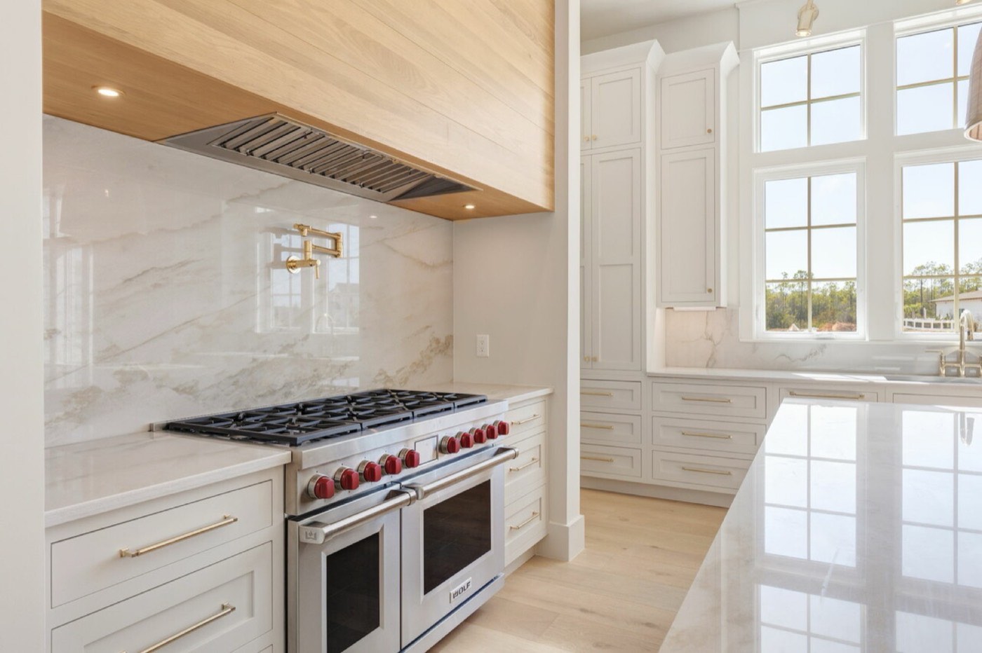 Covered Bridge Cabinetry Range wall with wood range hood (Farmington inset, white oak), available at Shoreline Cabinet Company in Wilmington, NC