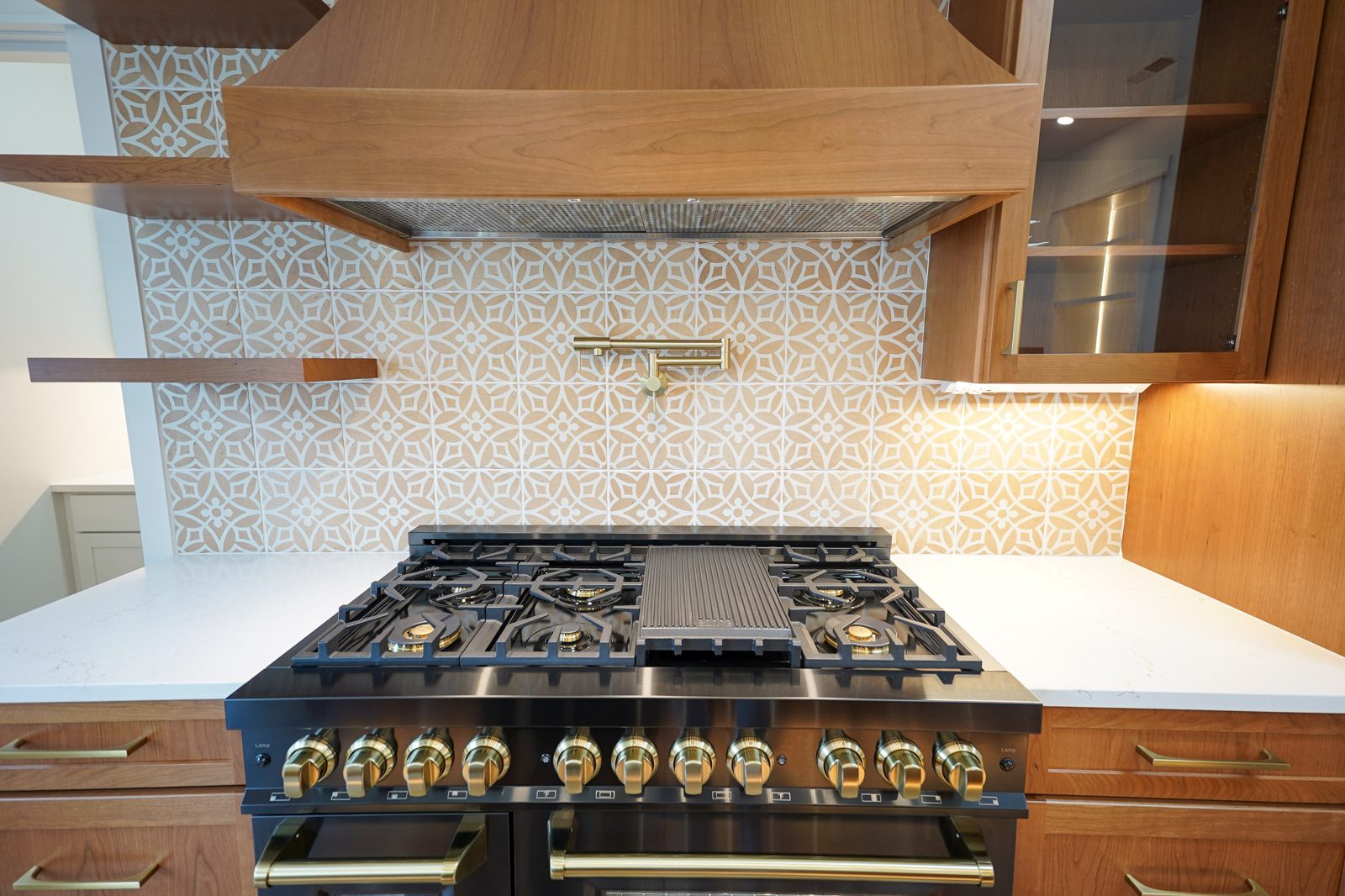 Brass knob detail under a cherry range hood by Shoreline Cabinet Company, Wilmington NC