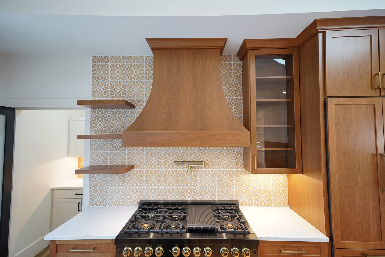 Cherry range wall with a wood hood and patterned tile backsplash by Shoreline Cabinet Company, Wilmington NC