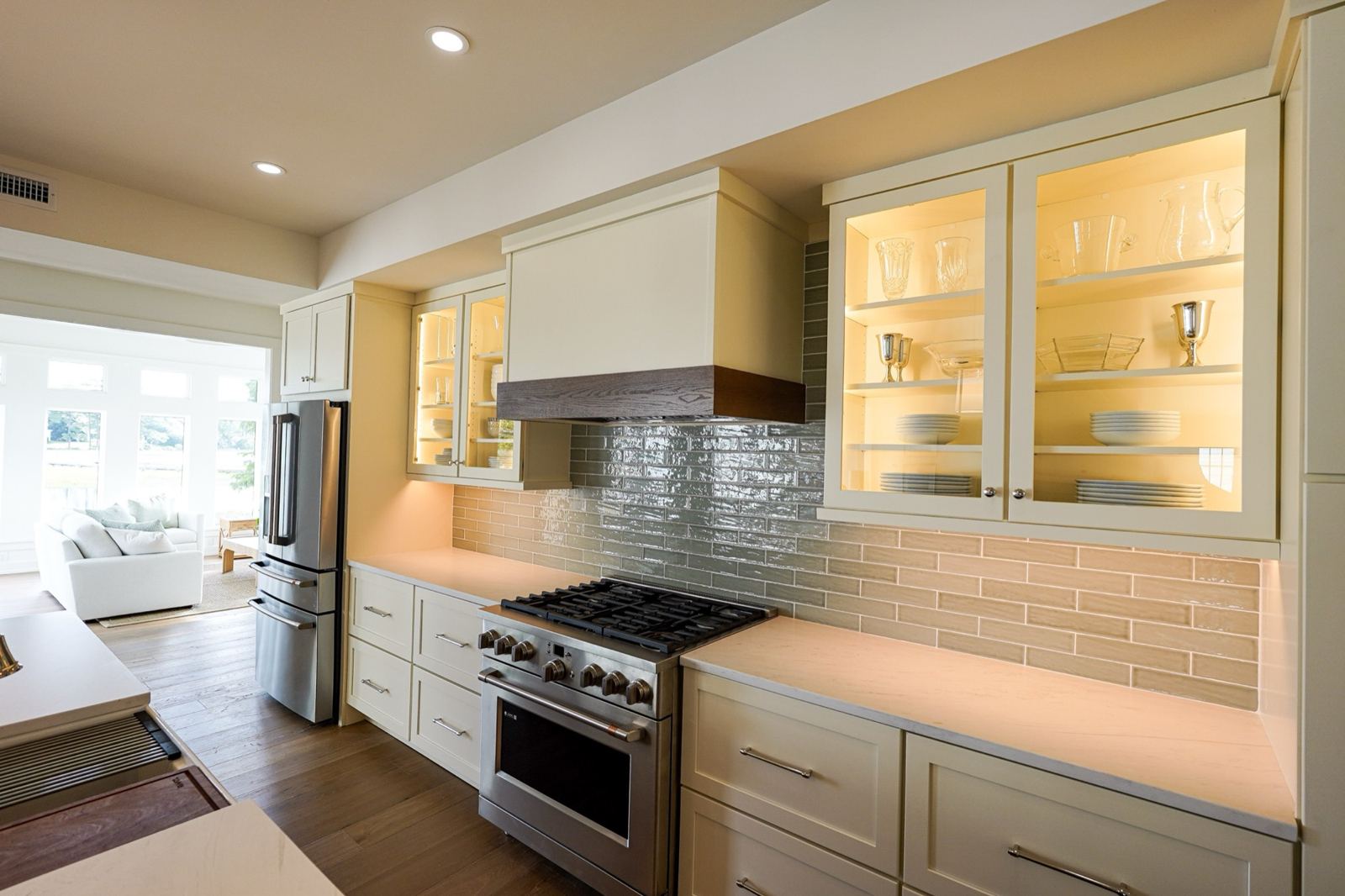 Lit glass-front upper cabinets on a range wall in a Wilmington, NC kitchen
