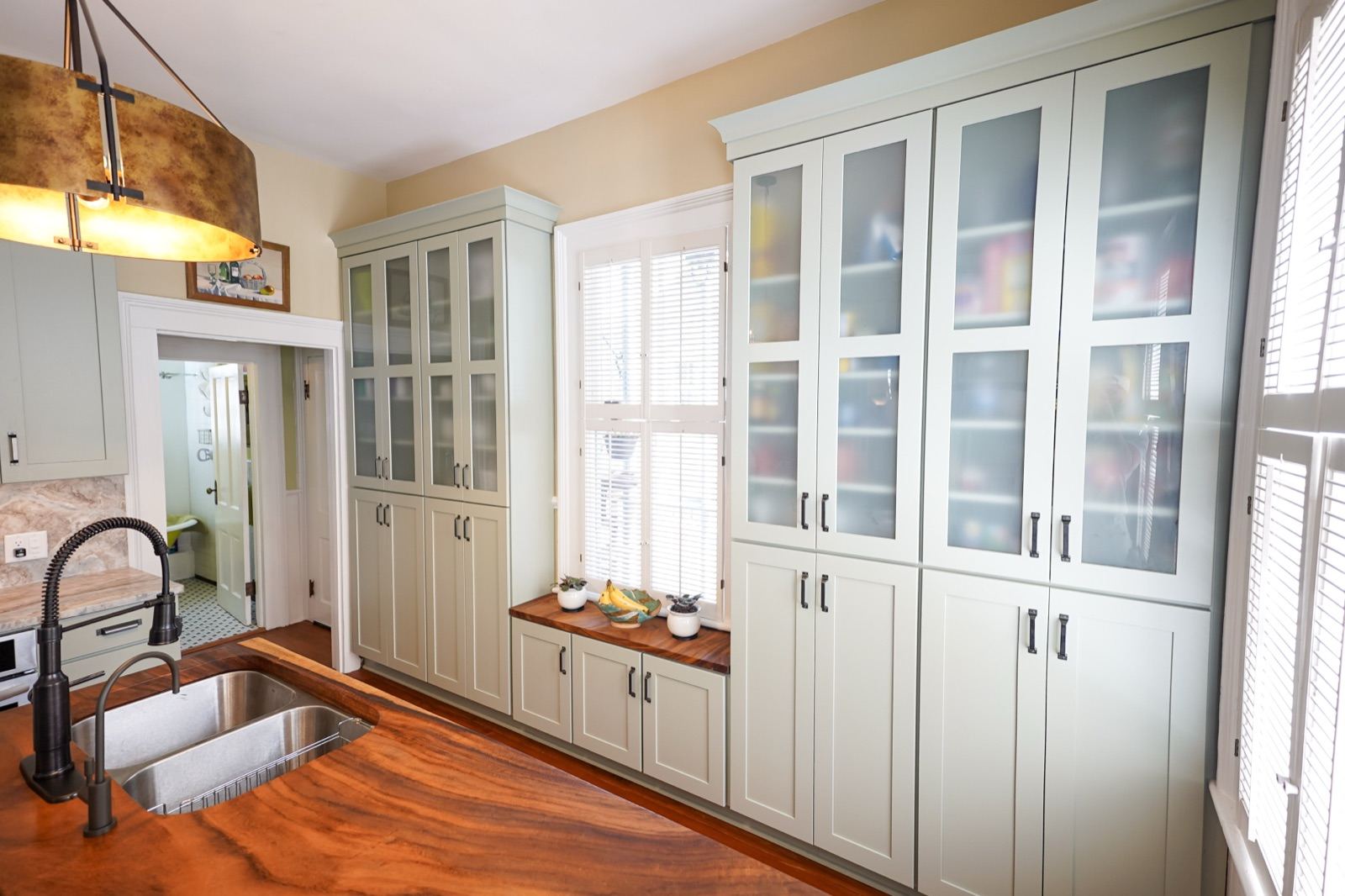 Sage glass-front cabinets with a butcher block counter by Shoreline Cabinet Company, Wilmington NC
