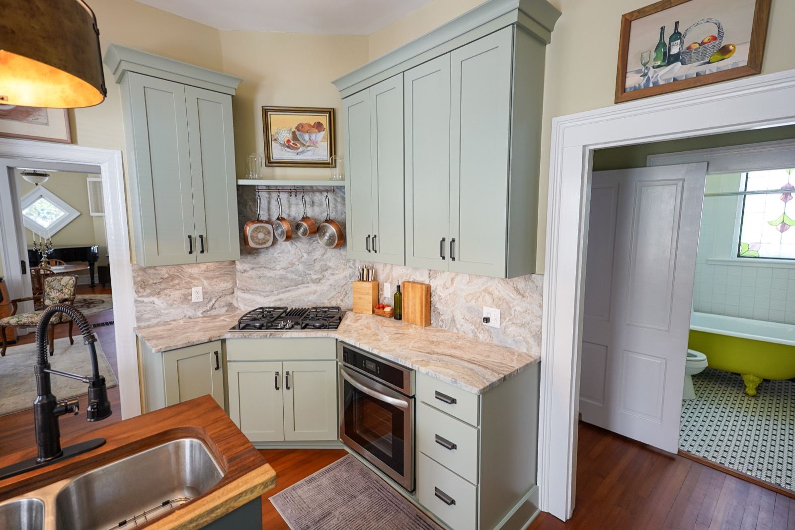 Sage green kitchen cabinets around a gas range by Shoreline Cabinet Company, Wilmington NC