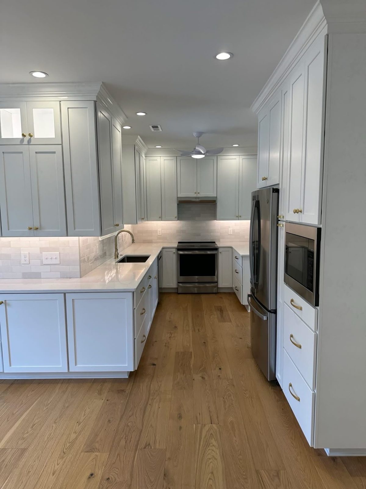 White L-shaped kitchen with stacked glass-front uppers by Shoreline Cabinet Company, Wilmington NC