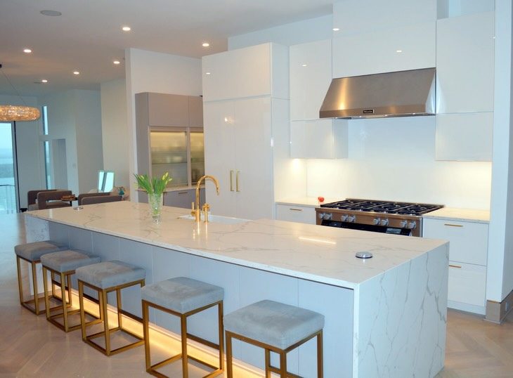 White modern kitchen with a lit waterfall island by Shoreline Cabinet Company, Wilmington NC
