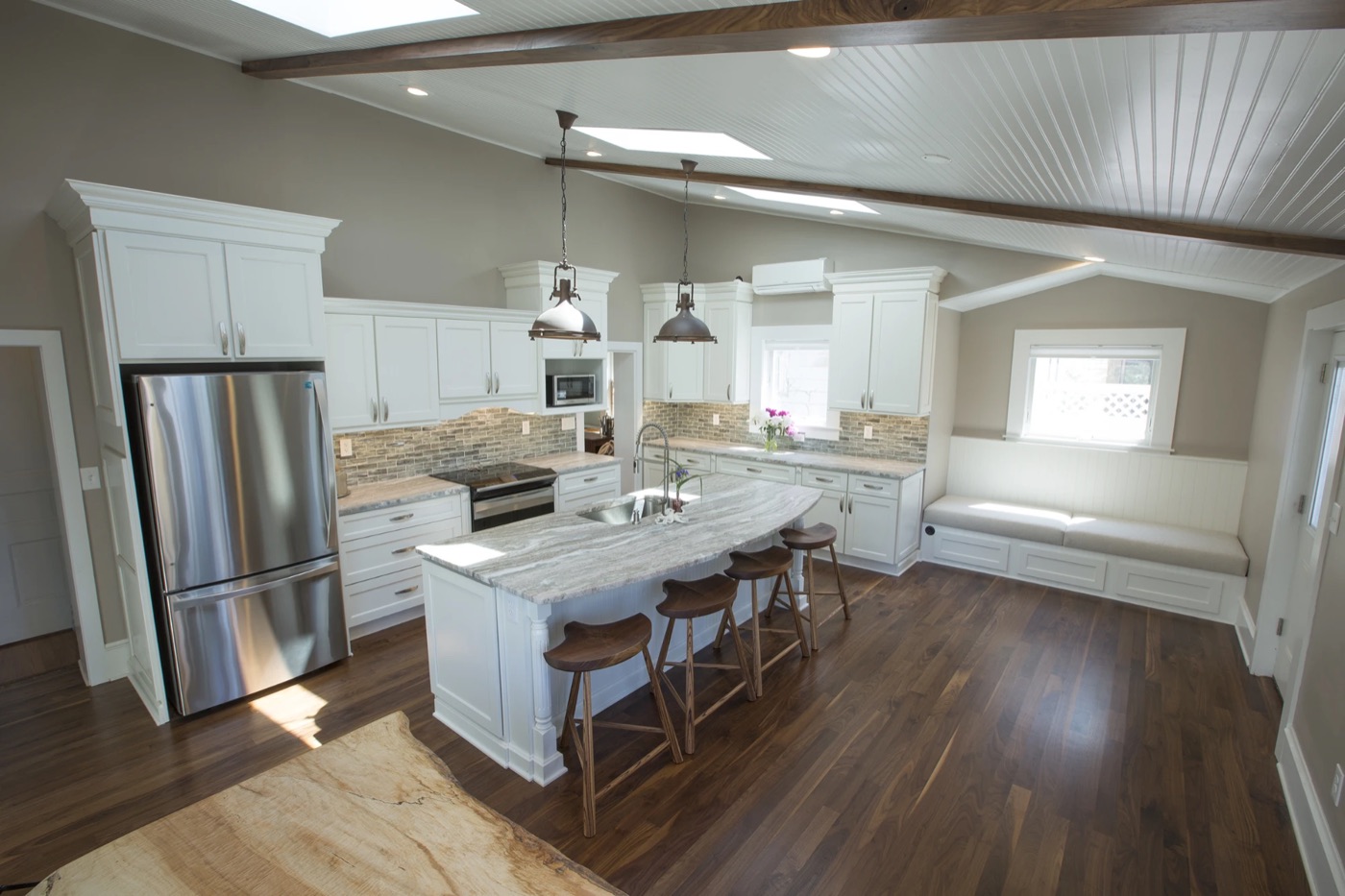 White shaker kitchen with a curved island, turned posts and a built-in window bench